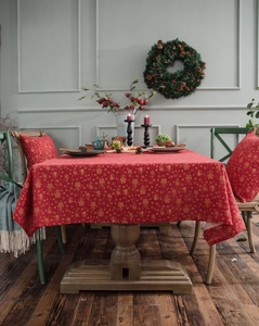 Close-up of red and gold Christmas tablecloth with festive bells and snowflakes