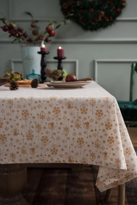 Detail view of cotton linen Christmas tablecloth with gold snowflake and bell print patterns