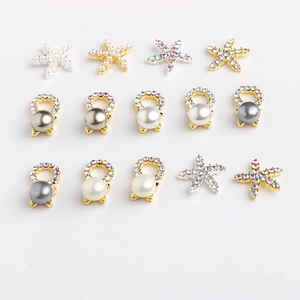 Detailed view of metal starfish and pearl nail art charms with rhinestone accents