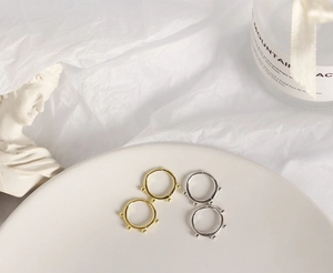 Detailed view of silver and gold beaded hoop earrings on a minimalist white ceramic tray