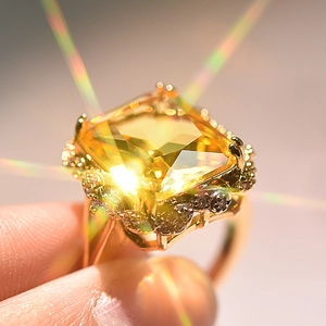 Close-up of golden ring with large square champagne stone and small crystal accents
