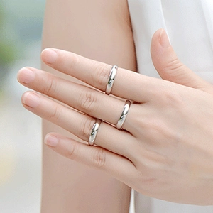 Close-up of three minimalist polished silver titanium steel rings worn on fingers