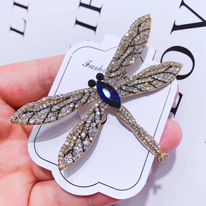 Detailed macro view of a vintage dragonfly brooch with blue gemstone and white crystals