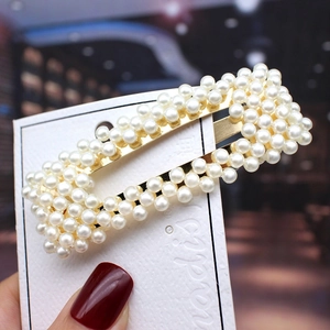 Close-up of elegant gold rectangular hair clip featuring white pearls and fashion jewelry card