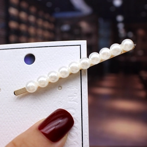 Detail of elegant gold-tone hair clip with eleven round pearls on display card