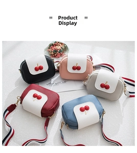Multiple mini cherry crossbody bags in diverse colors on a stylish textured surface