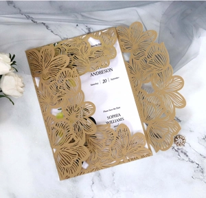 Detailed laser-cut gold floral invitation sleeve with white insert card on marble surface