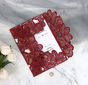 Detail of laser-cut hollow floral invitation card with white inner page and deep red cover