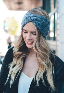 Detail of greyish-blue knitted headband featuring a chunky twist knot design for winter