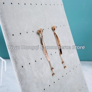 Close-up of rose gold tassel earrings displayed on a professional velvet jewelry stand