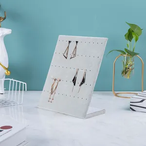Detailed view of grey velvet L-shape earring display stand on white marble surface