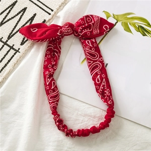 Detail of red paisley cotton headband featuring a large bow and elastic band design