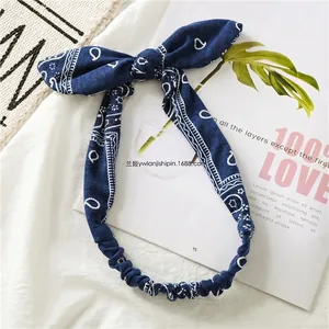 Detail of navy blue paisley cotton headband with rabbit ears on textured fabric