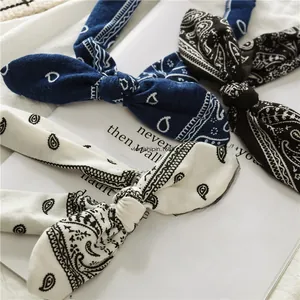 Detailed view of three paisley print bunny ear headbands in navy, black and cream colors
