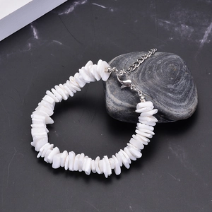 Handmade white fragmented shell bracelet with silver lobster clasp on marble stone
