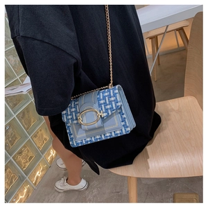 Detail of tweed crossbody bag with blue leather trim and golden chain strap
