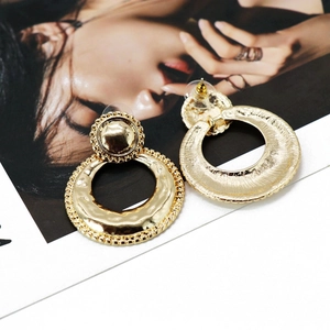 Detailed close-up of gold vintage textured hoop earrings on a fashion magazine card