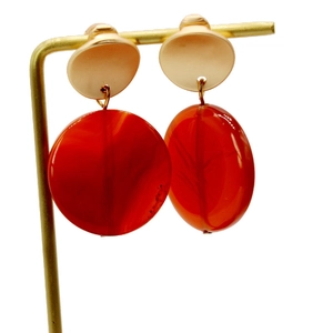 Detailed macro view of red translucent agate earrings with golden metal studs