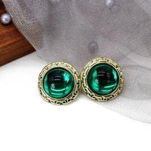 Detail of vintage emerald green earrings with textured gold-tone alloy frame and pearl accents