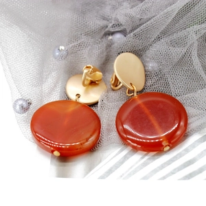 Elegant matte gold drop earrings with translucent orange round stones on grey mesh background