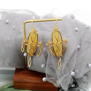 Detail of yellow oval gemstone earrings with gold wire wrap on a jewelry stand