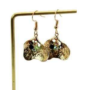 Detail of golden ginkgo leaf earrings with colorful beads on a jewelry display stand