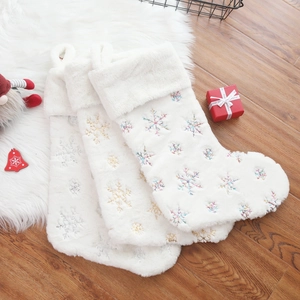 Three plush white Christmas stockings featuring silver, gold and colored snowflake embroidery