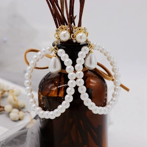 Detail of vintage gold earrings with pearls and crystals hanging on a brown glass bottle