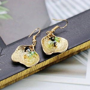 Detailed macro of golden leaf earrings with vintage green and black beaded accents