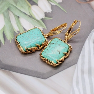 Detailed shot of golden vine-wrapped rectangular turquoise earrings with white zircons