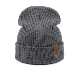 Close-up of dark grey ribbed knit beanie with brown leather tag and metal stud detail