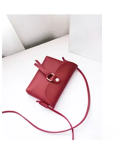 Detail of a dark red matte leather mini crossbody bag with gold metal hardware