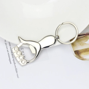 Creative silver thumb-shaped metal keychain bottle opener on a white ceramic plate