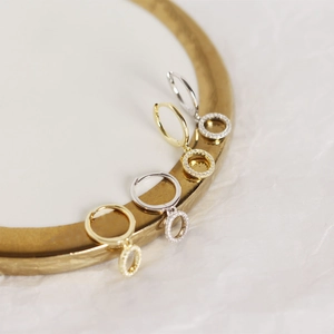 Close-up of gold and silver S925 earrings with diamond pendants on a golden tray