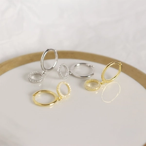 Macro shot of silver and gold geometric drop hoop earrings with sparkling rhinestones