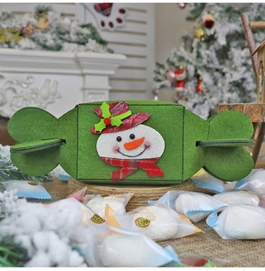 Macro shot of green felt snowman candy bag with a cozy festive fireplace background