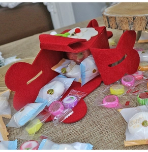 Close-up of a red felt Christmas candy bag with a 3D Santa Claus figure on a rustic table