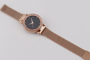 Detailed macro view of rose gold Milanese strap and black starry sky dial quartz watch