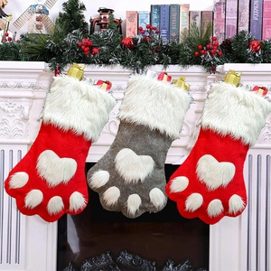 Three paw-shaped Christmas stockings with plush heart hanging on fireplace mantel
