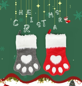 Detail of red and grey dog paw Christmas stockings with heart patterns on green background