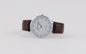 Detail of minimalist quartz watch with polished silver case and brown leather strap