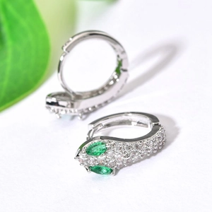 Detailed macro view of silver snake earrings with green and clear zircon crystals