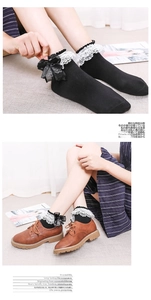 Detail of Lolita cotton socks with white lace trim and black ribbon bow decorations