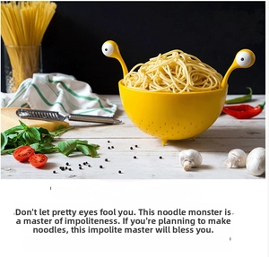 Detail of yellow monster pasta colander with googly eye handles on a kitchen table