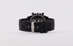 Close-up of black rubber sports watch strap with red stitching and metal pin buckle
