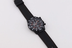 Detailed macro view of black quartz sports watch dial with orange hands and rubber strap