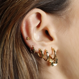 Close-up of s925 silver gold-plated interlocking hoop earrings with sequin charms on ear