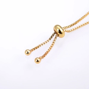 Detailed view of a gold plated slider clasp bracelet with adjustable chain and bead ends