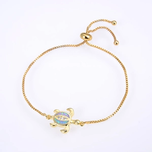 Detailed macro view of a gold-plated turtle charm bracelet with blue opal and zircons