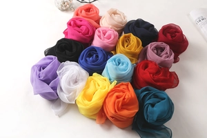 Multiple colorful chiffon scarves rolled in flower shapes on white background detail